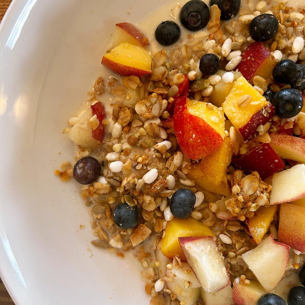Bowl of granola with fresh blueberries and peach slices.