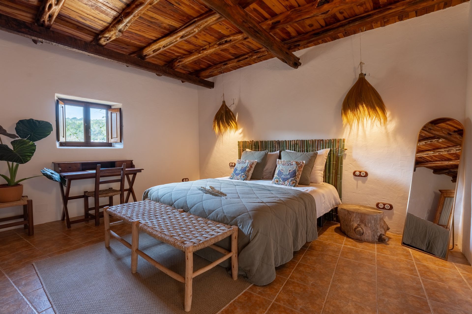 A bright, bedroom with lamps by the bed and pot plant