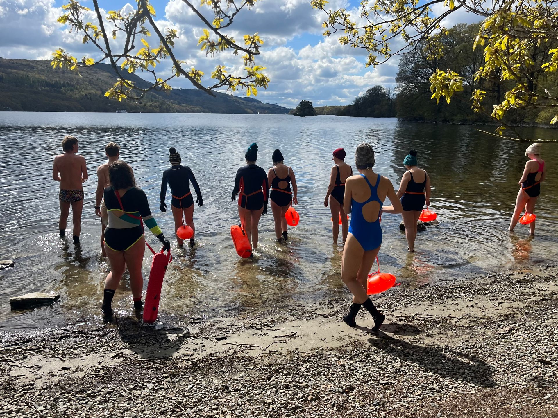 people walking into a lake for a swim