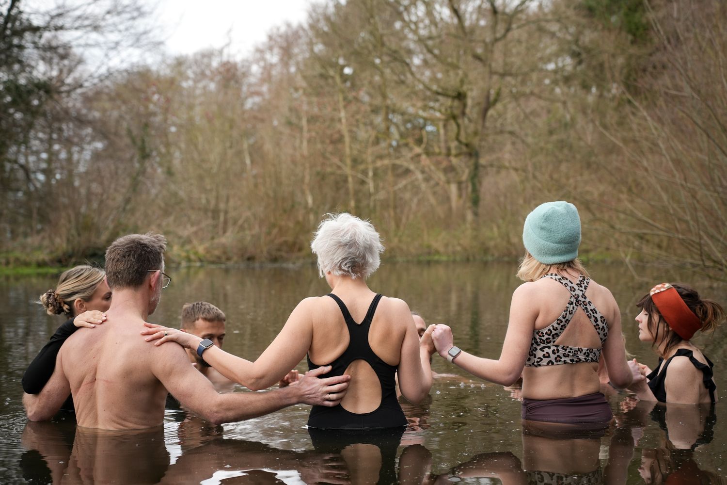 People standing in a pond in cold water holding hands