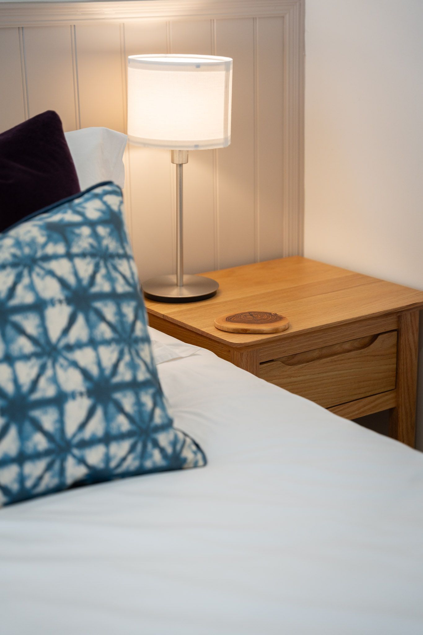 Cushions on a white ebd with bedside lamp