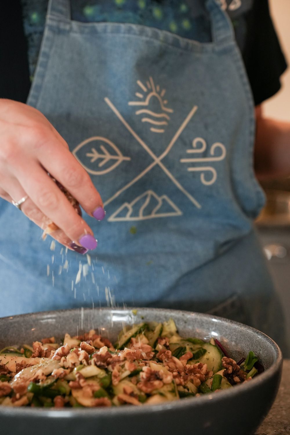 A lady sprinkling a salad into a bowl