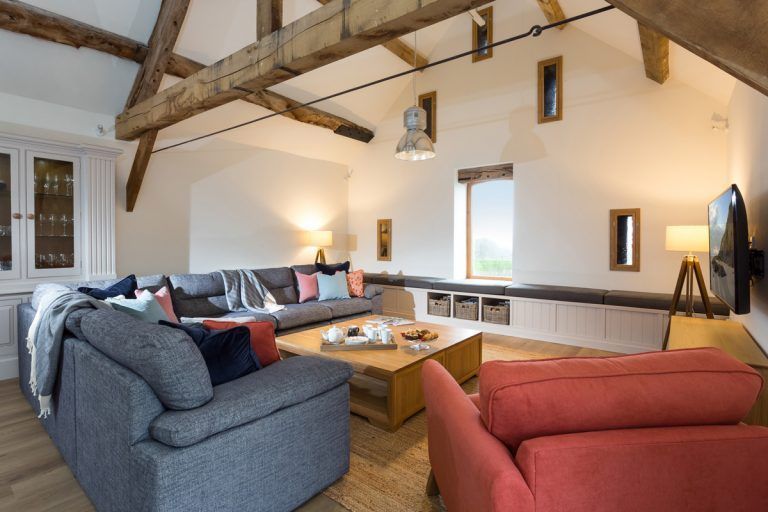 Cozy living room with gray sectional sofa, red armchair, wooden beams, and a large window.