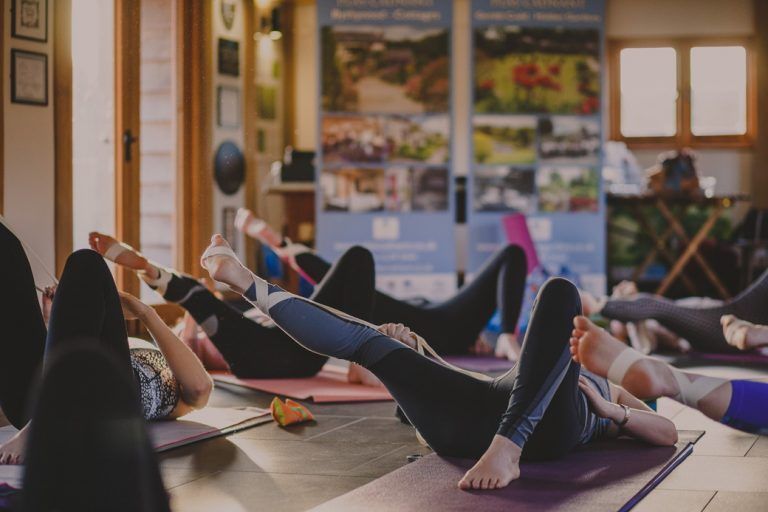 People on yoga mats, legs raised, practicing yoga indoors.