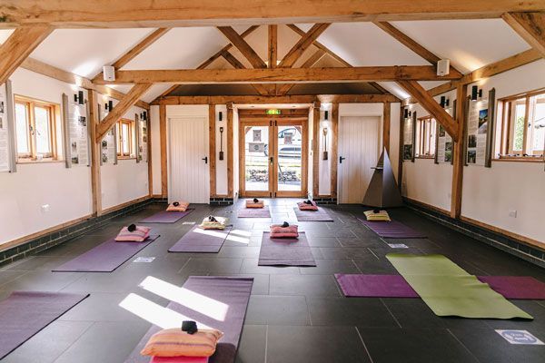 Yoga studio with mats, pillows, and wood beams.