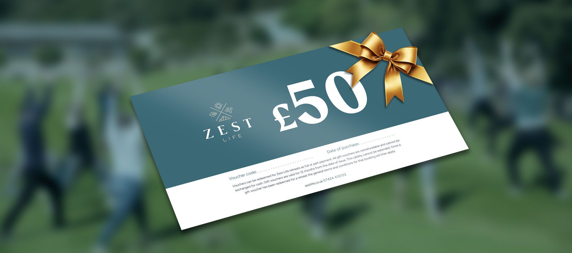 Gift card for £50 with gold bow, teal and white design, blurred background of people on grass.