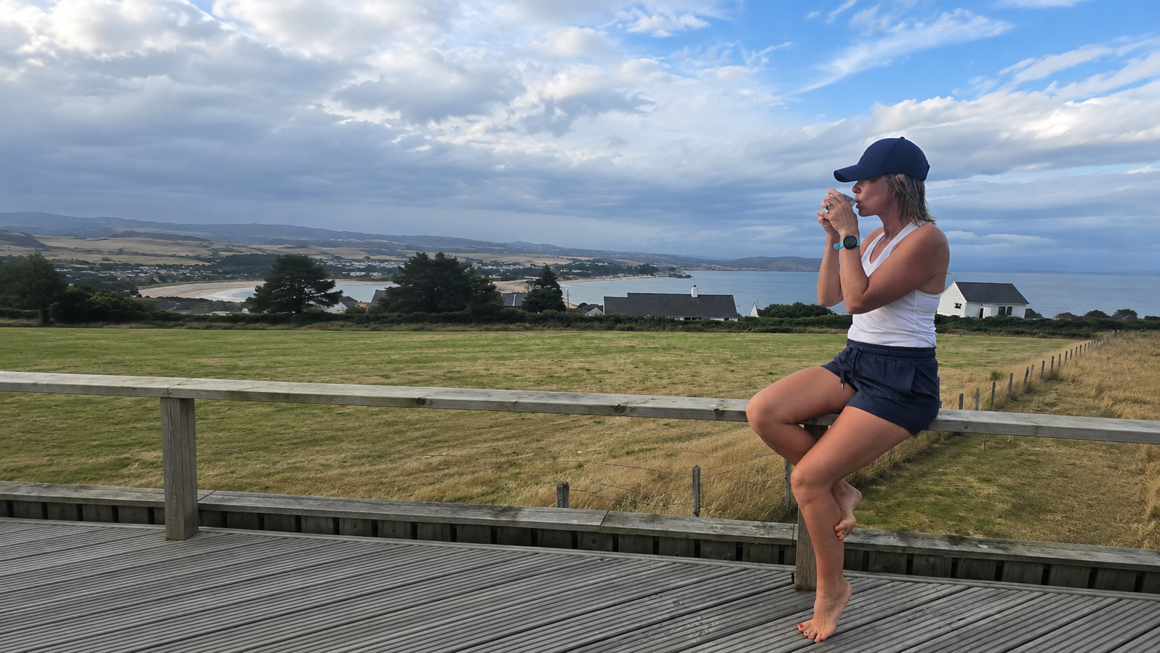 laura sitting drinking tea on deck by the sea