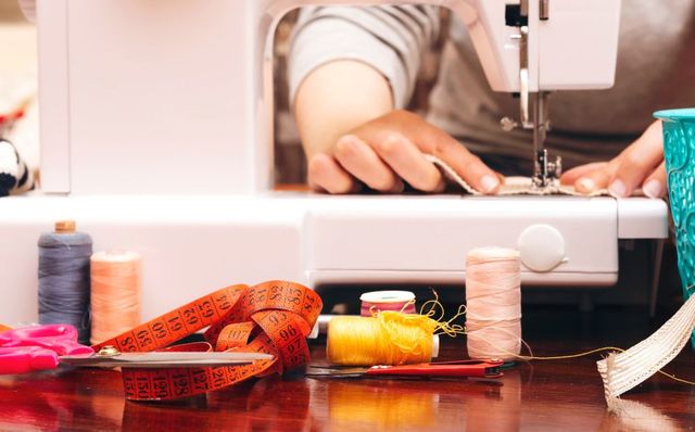 A Person Is Using A Sewing Machine On A Wooden Table — Coastal Monogramming In Maroochydore, QLD
