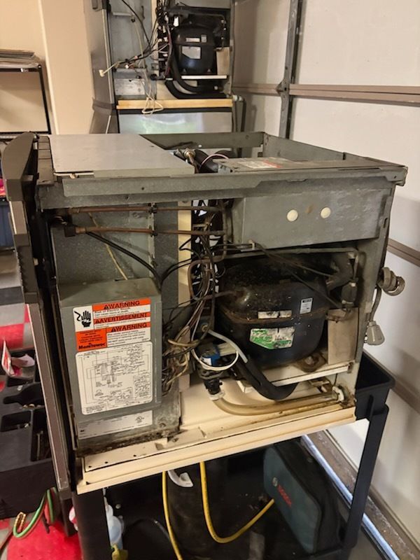 Open HVAC unit on a shelf, showing wiring, compressor, and metal housing components.