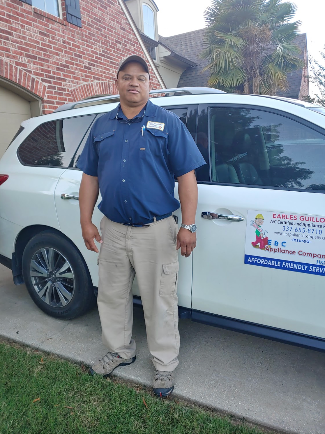 Man standing beside a white SUV with company logo in a driveway