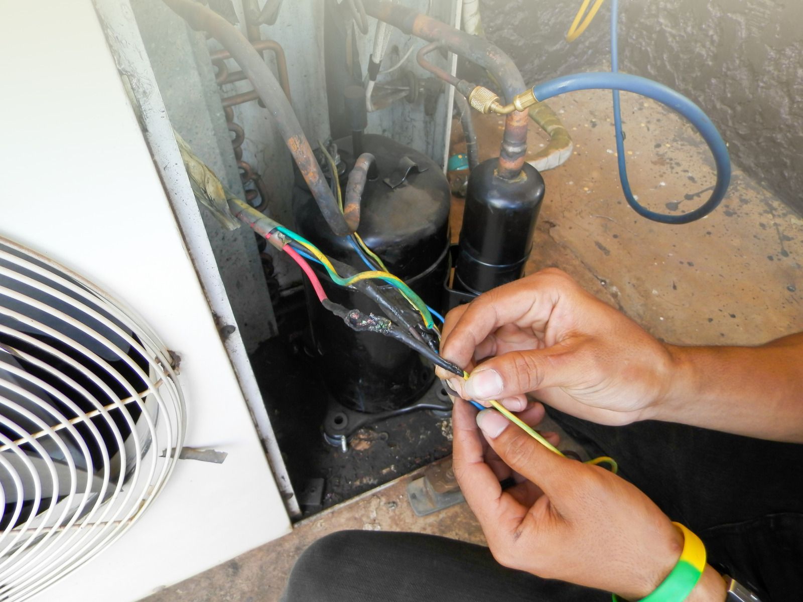Hands wiring a refrigeration compressor unit with multicolored cables