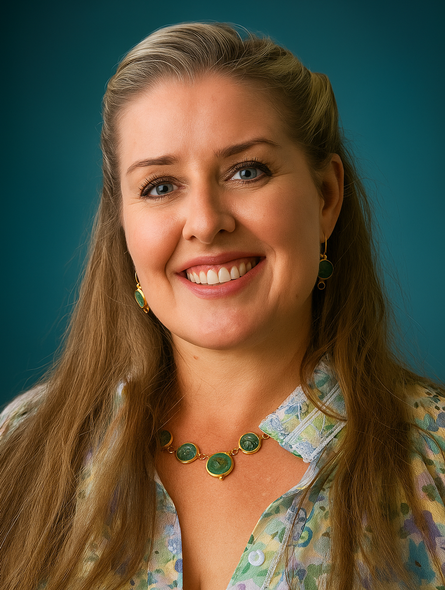 Smiling woman in a floral blouse, wearing a green necklace, against a blue background