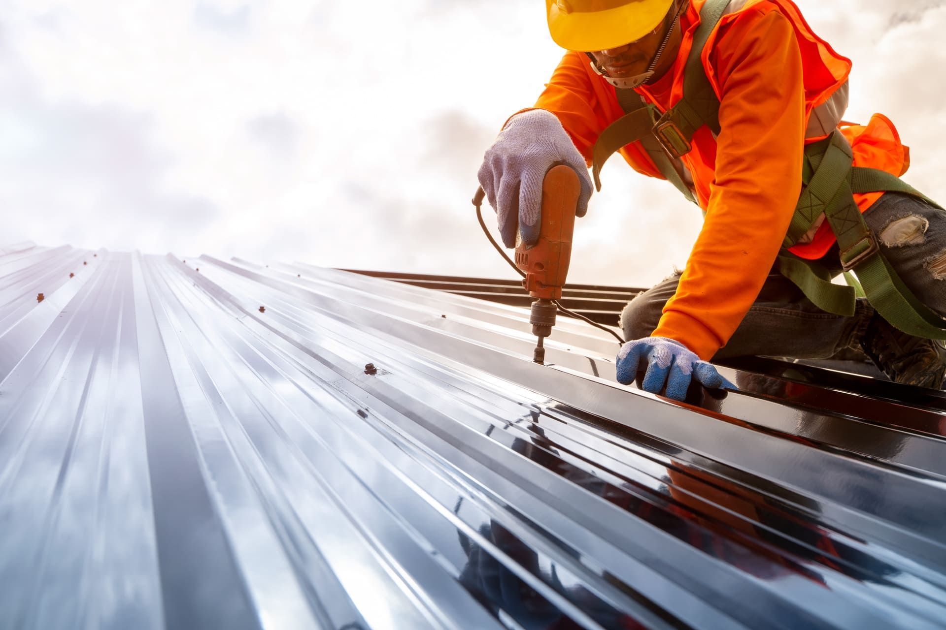Construction worker install new roof,Roofing tools,Electric drill used on new roofs with Metal Sheet