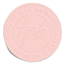 A circular pale pink emblem with a textured surface, featuring the embossed text