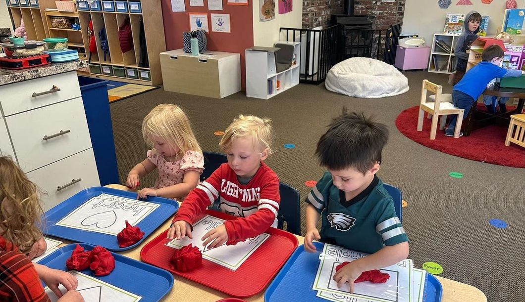 A group of children are sitting at a table in a classroom.