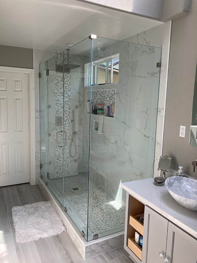 Modern bathroom with glass shower, marble tiles, and vanity.