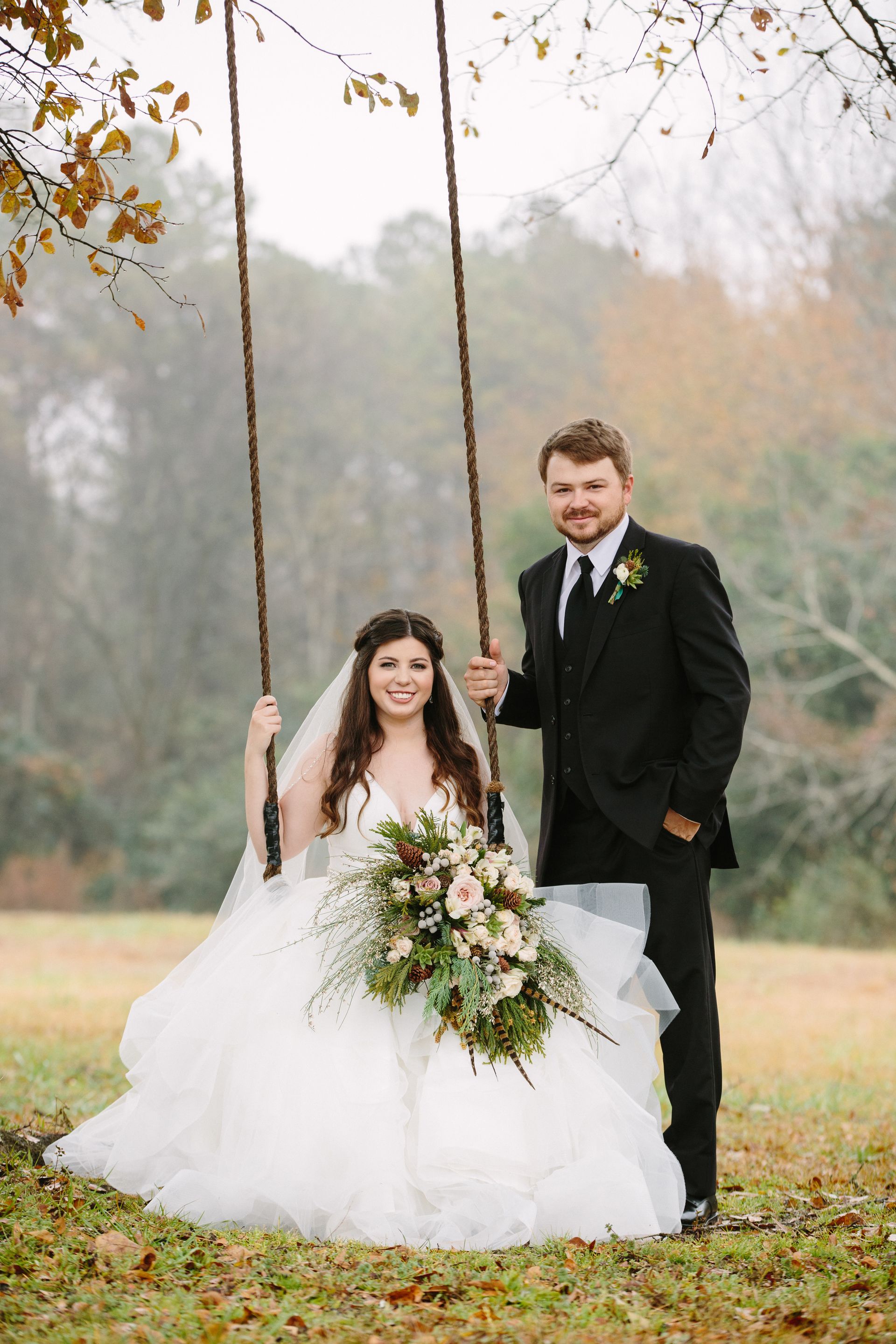 groom pushing bride on rope swing