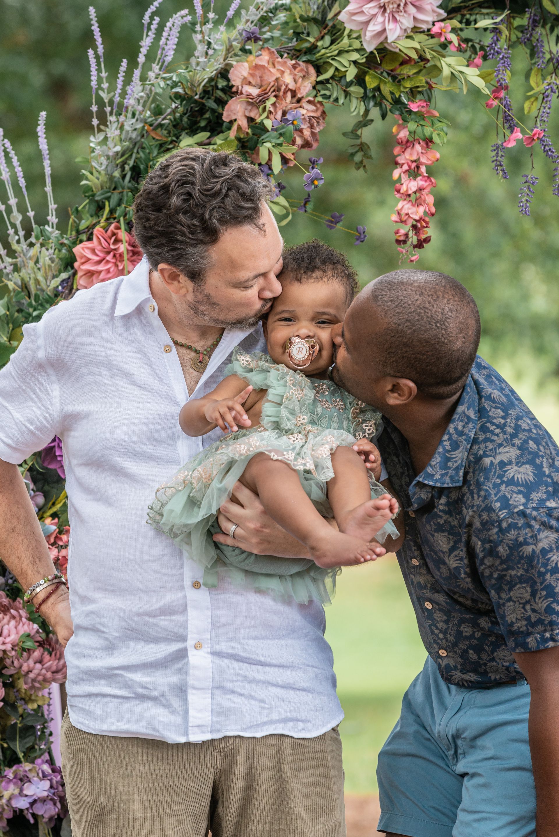 men kissing toddler's cheek