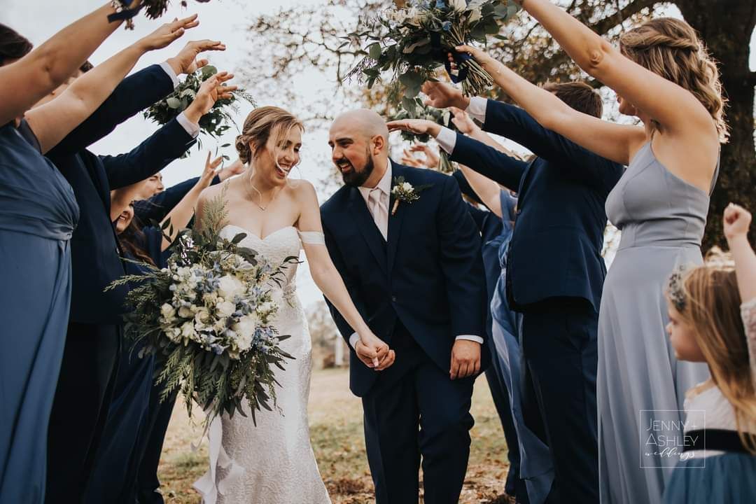 groom and bride walking through wedding party's arms