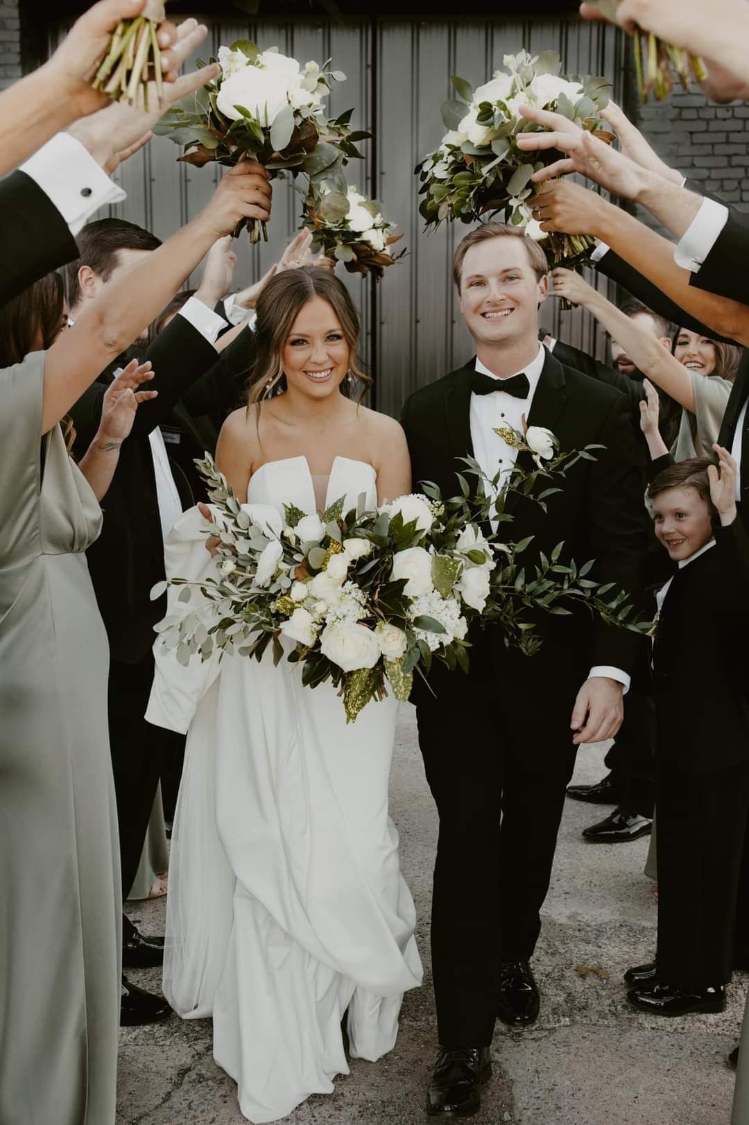 bride and groom walking through bridesmaids bouquets