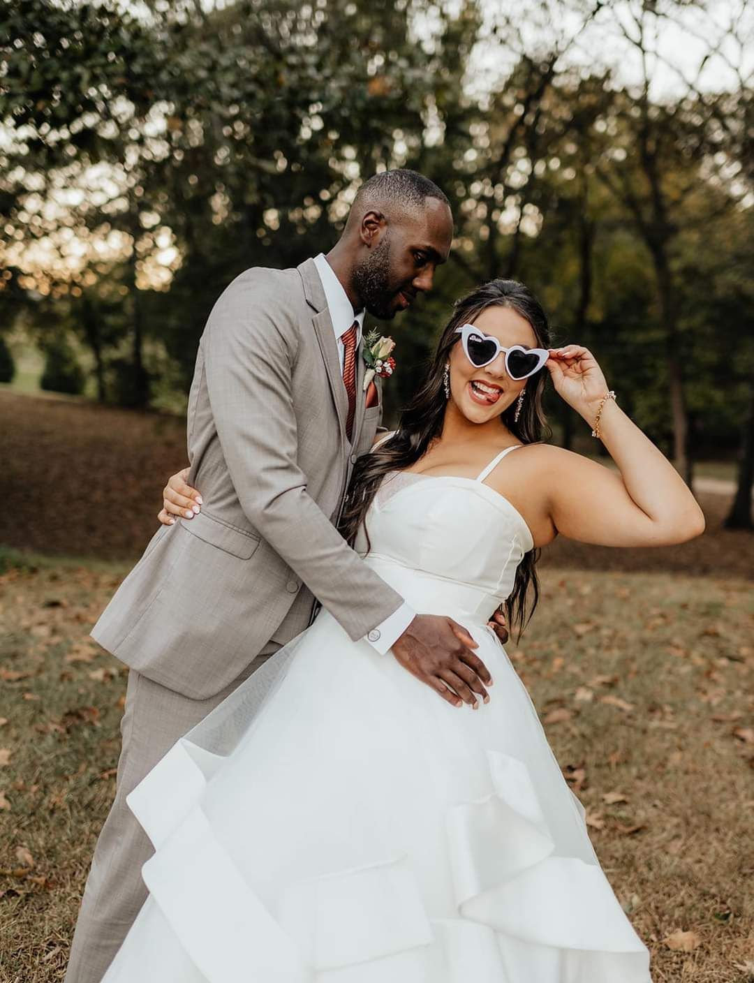 groom embracing bride wearing heart sunglasses