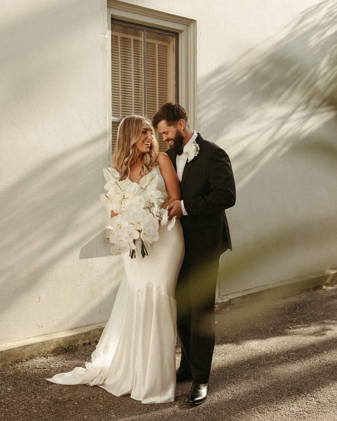 bride and groom posing in front of window
