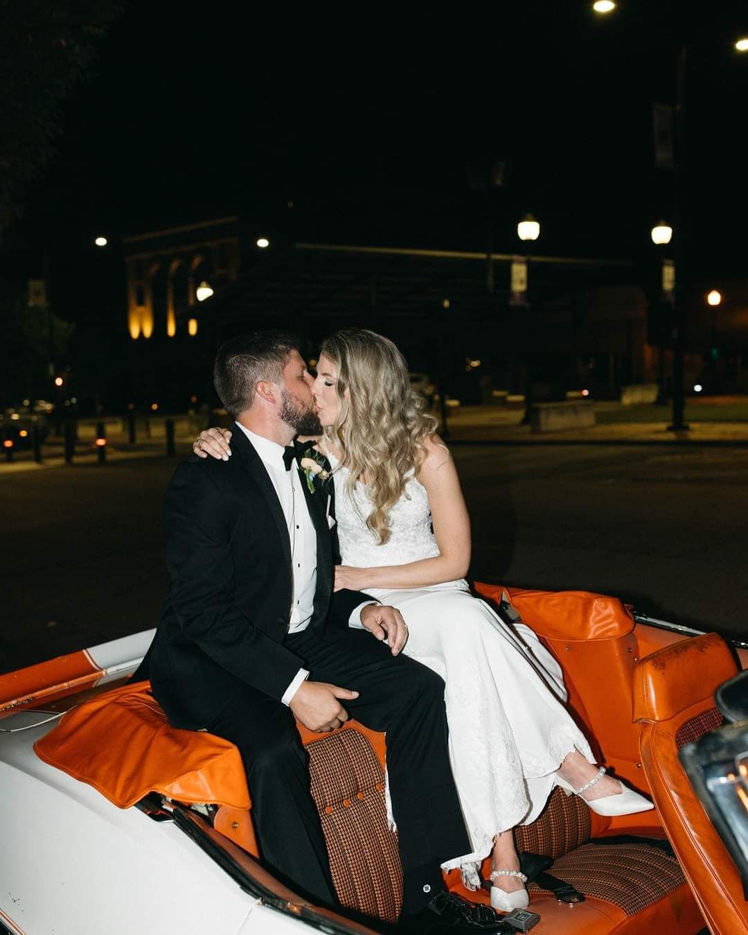 bride and groom kissing in the back of vintage convertable