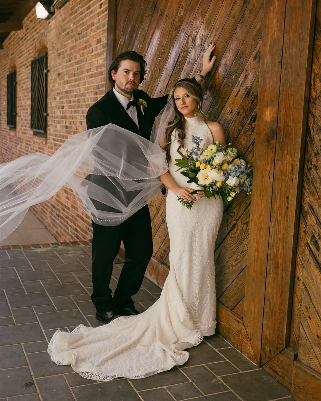 bride and groom leaning against large wooden door