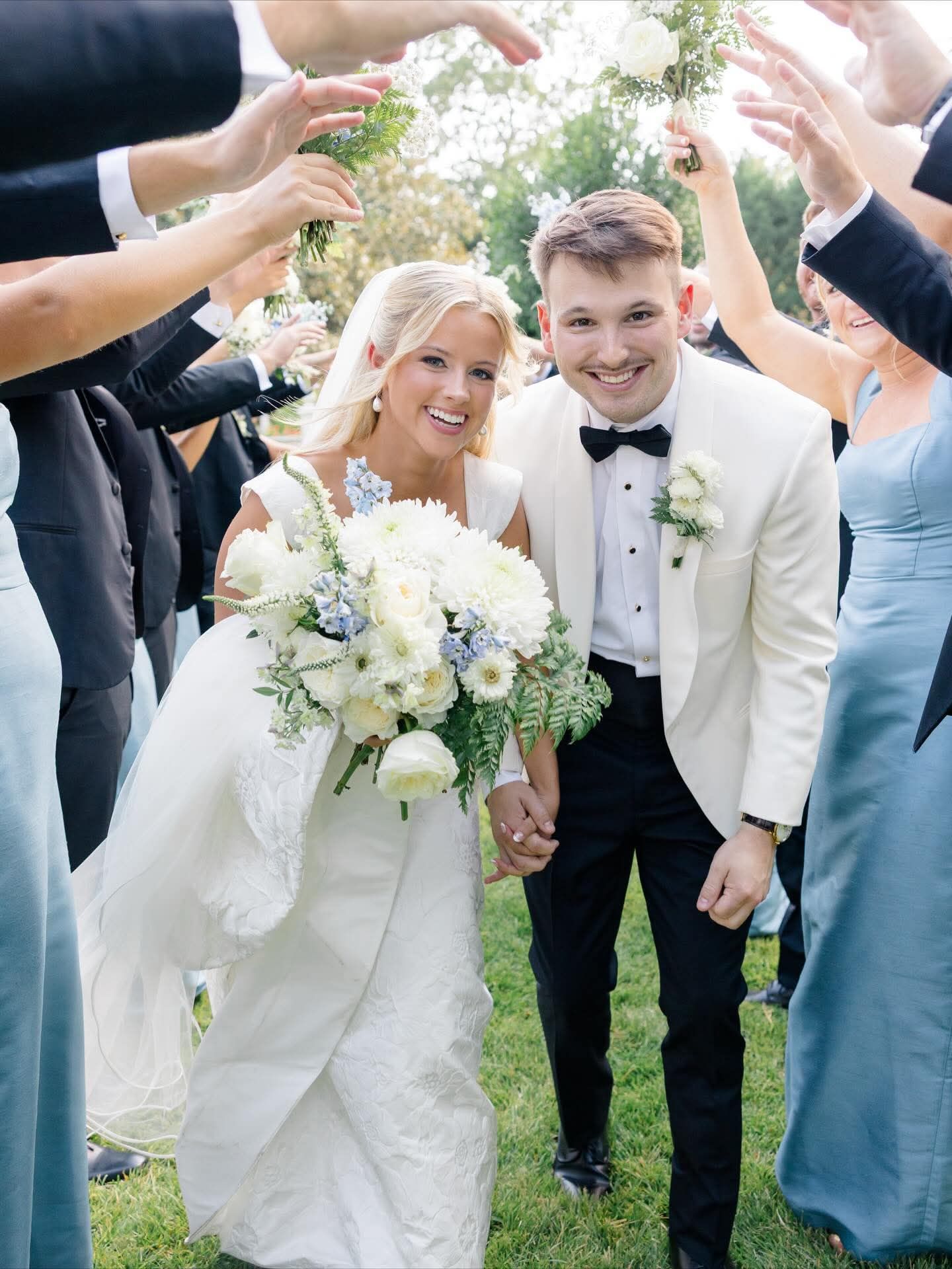 bride and groom walking under wedding party's arms