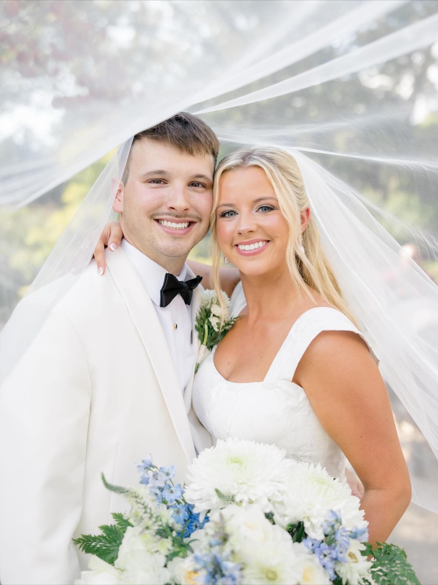 bride and groom smiling under bride's veil