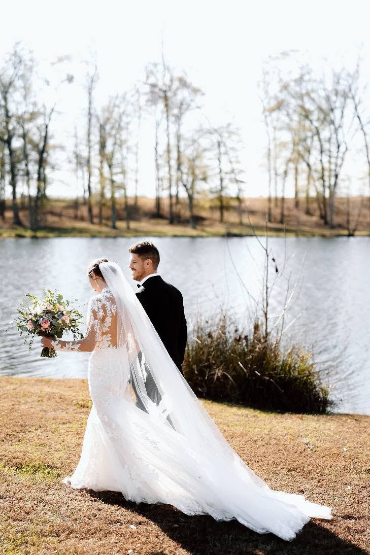 bride and groom walking in front of pond