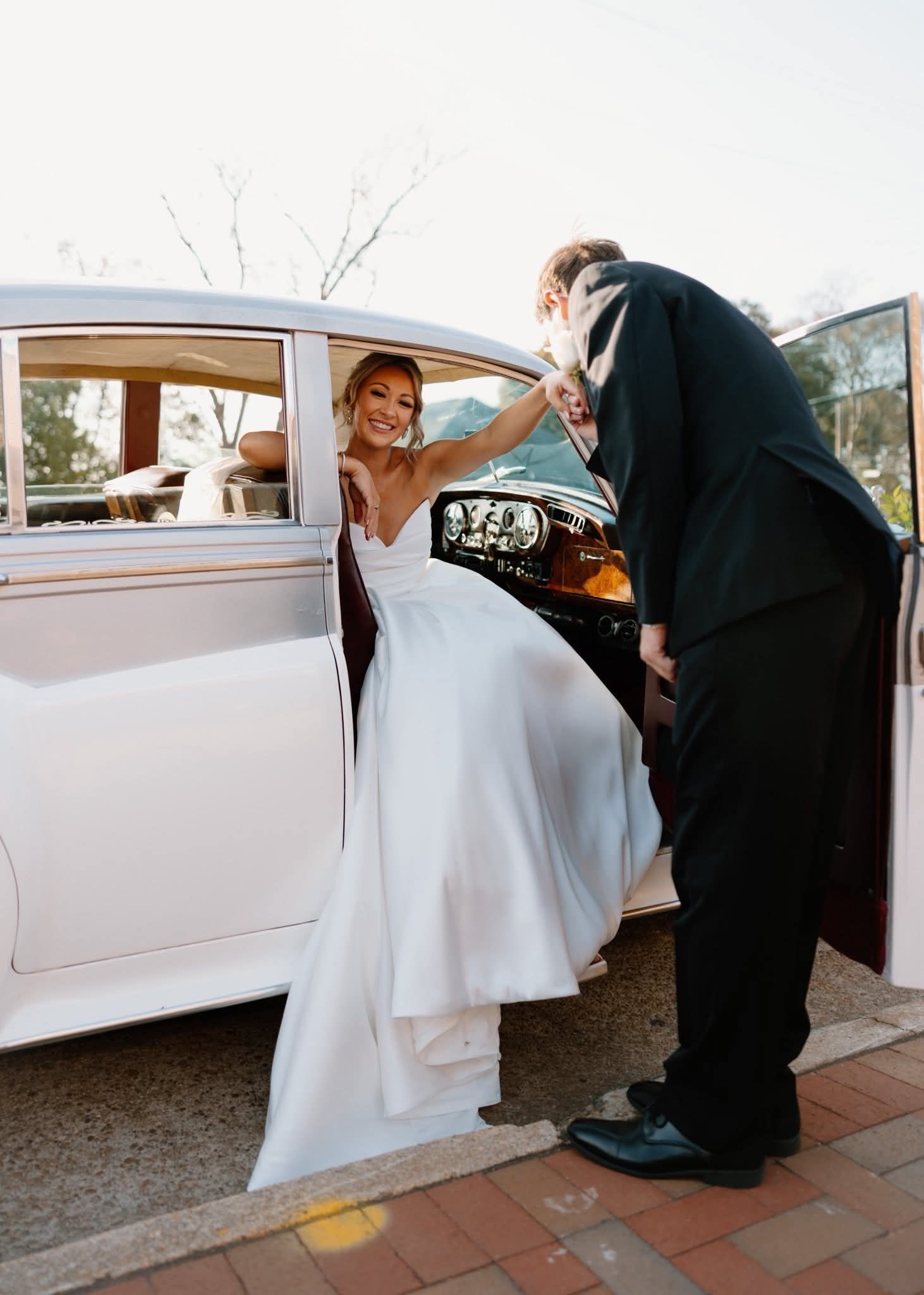 groom helping bride out of vintage car