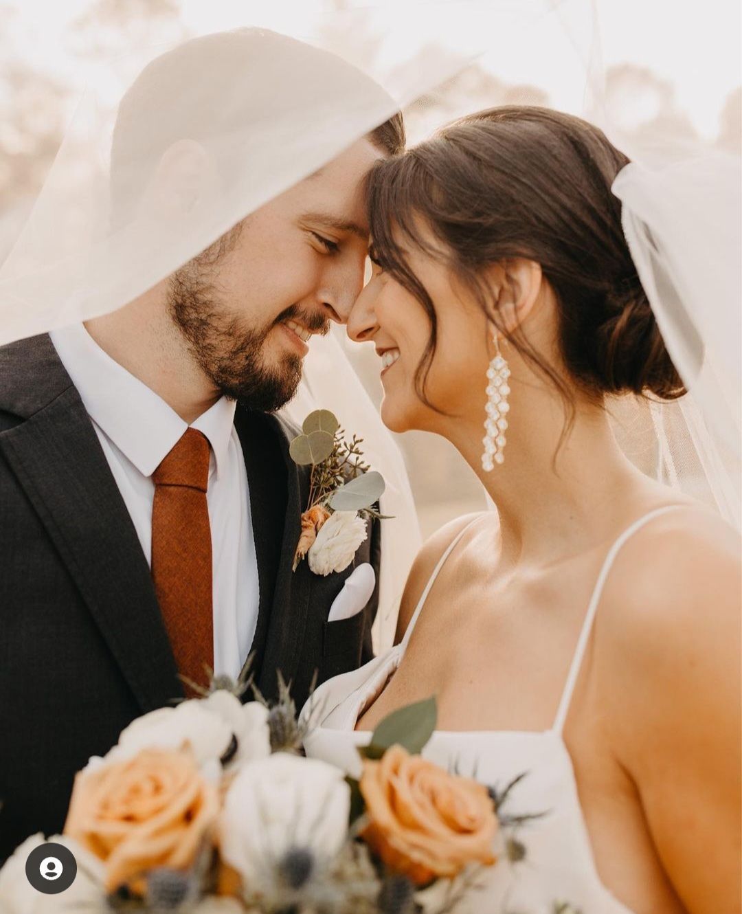 bride and groom smiling covered in bride's veil
