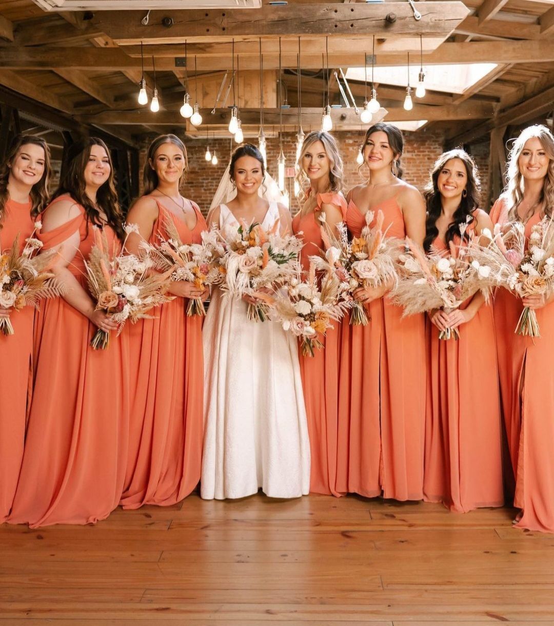 bride with bridesmaids in orange dresses with boho neutral bouquets