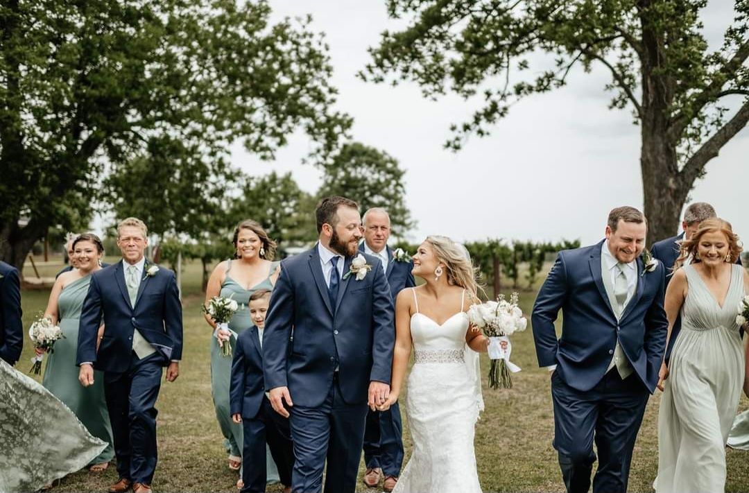 bride, groom, and wedding party walking through vineyard