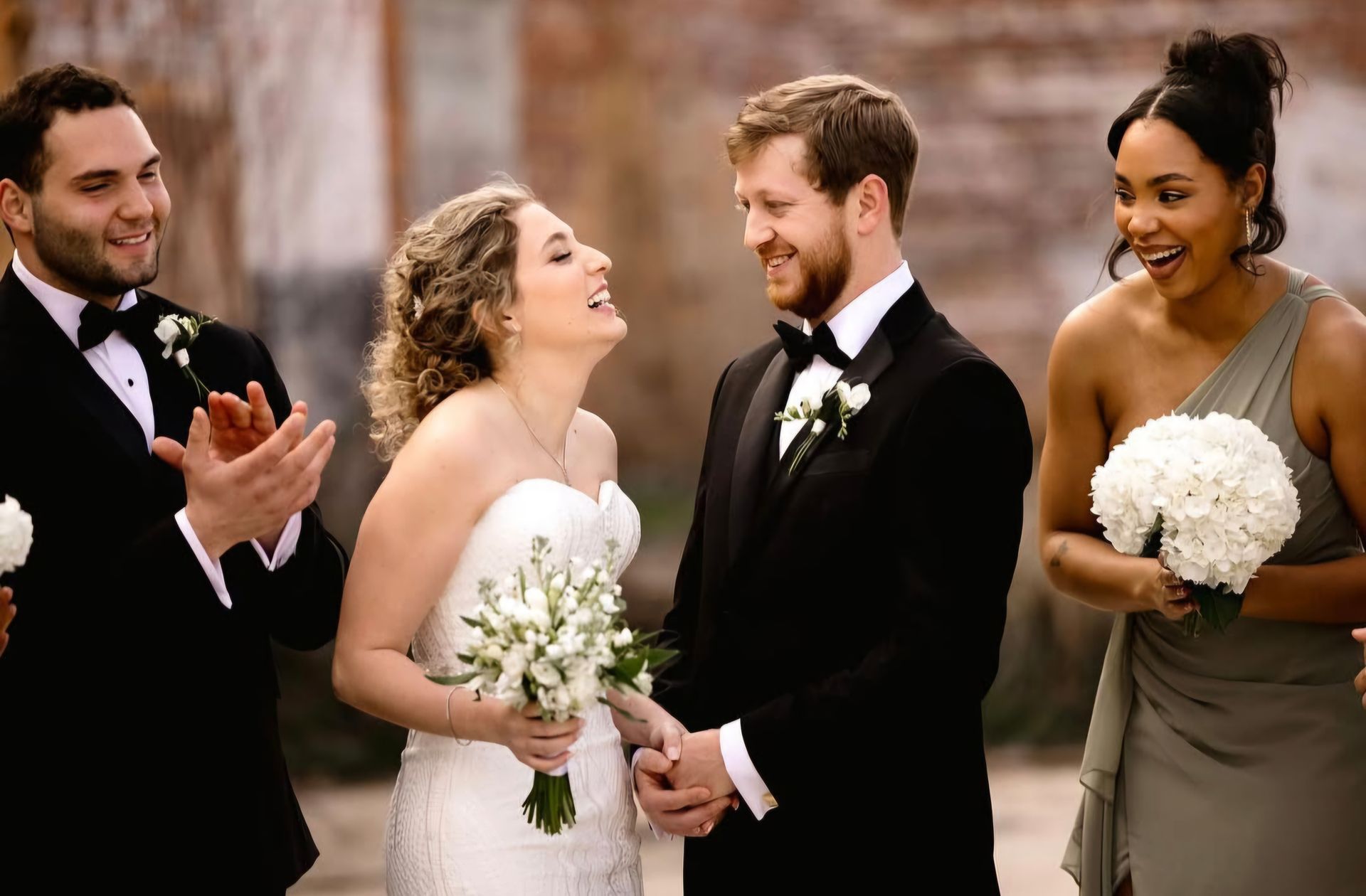 bride and groom smiling while wedding party applauds
