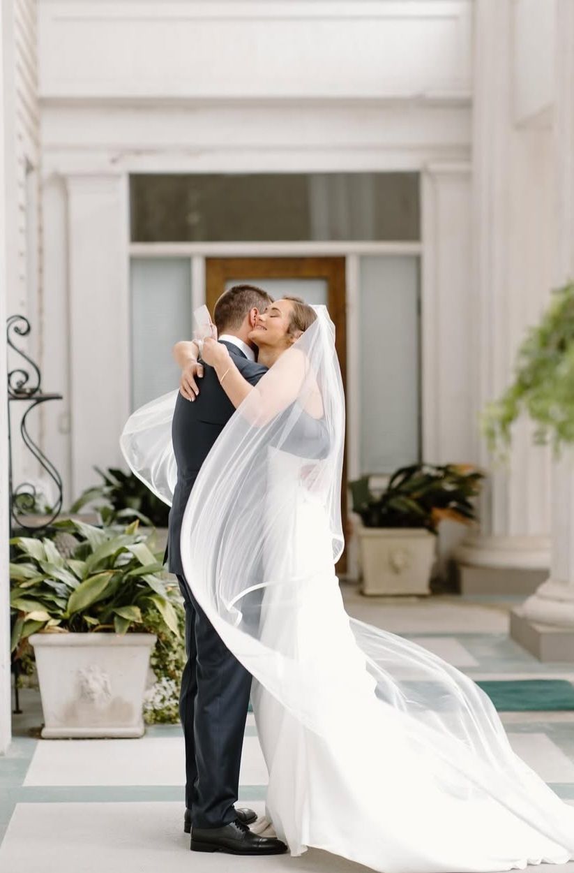 bride and groom hugging surrounded by flowing veil