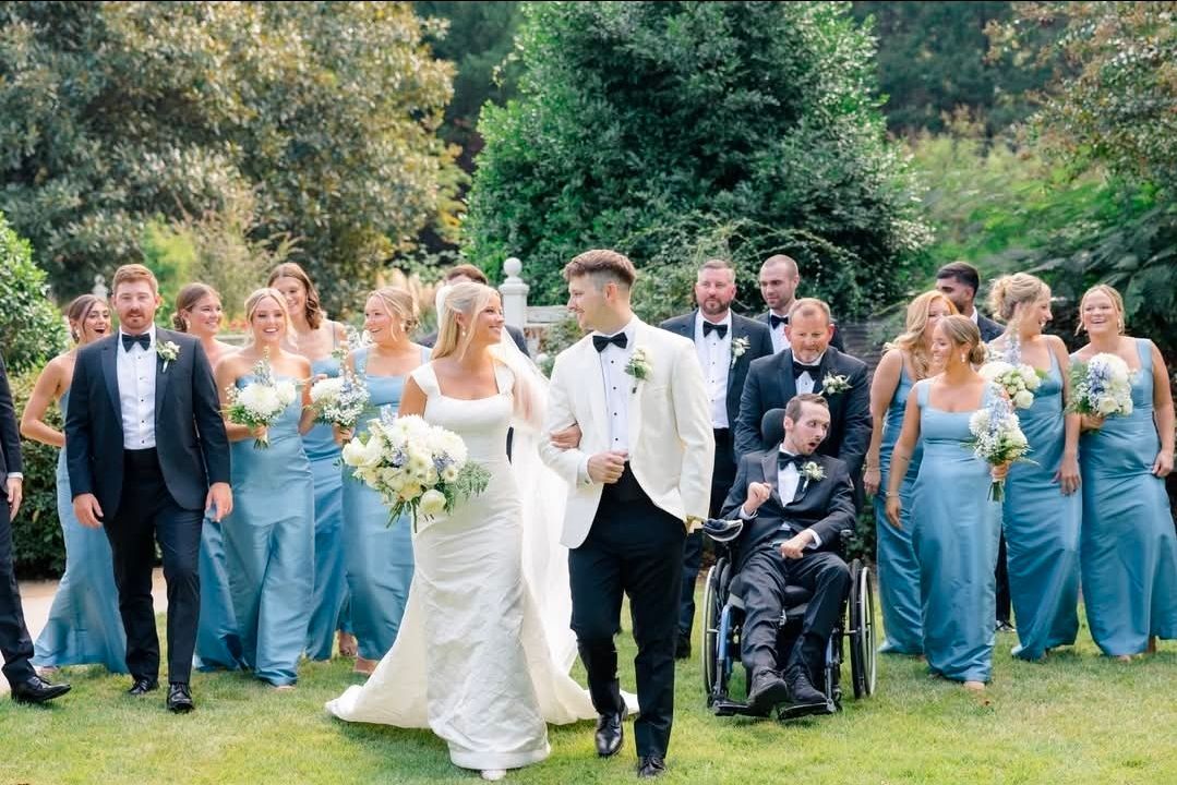 bride and groom walking through green lawn surrounded by wedding party