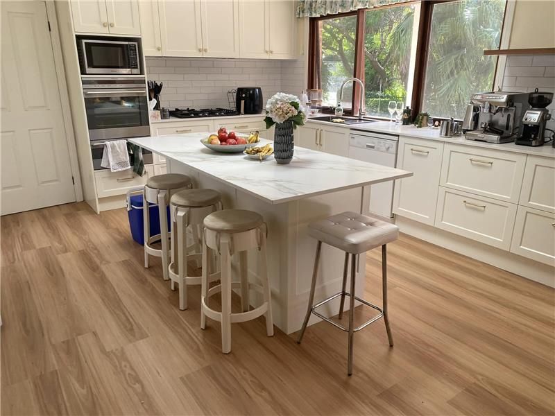 A Kitchen With a Large Island in the Middle and Stools — Kenross Kitchens In Avoca Beach, NSW