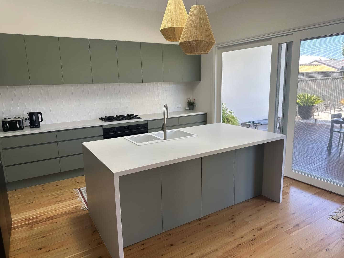A Kitchen With a Large Island and Sliding Glass Doors — Kenross Kitchens In Ettalong Beach, NSW