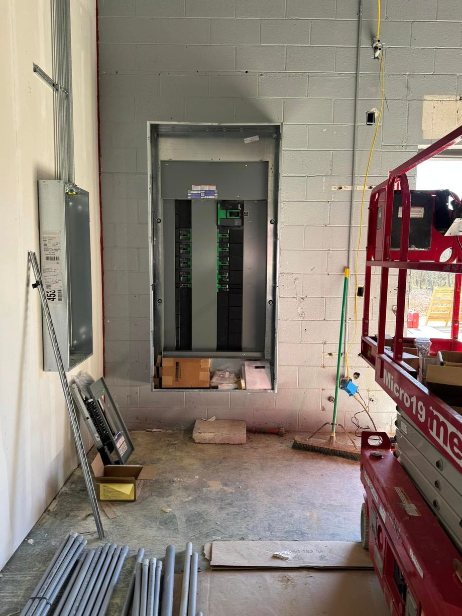 Interior work area with an open elevator shaft, cinderblock walls, and a red lift on the right.