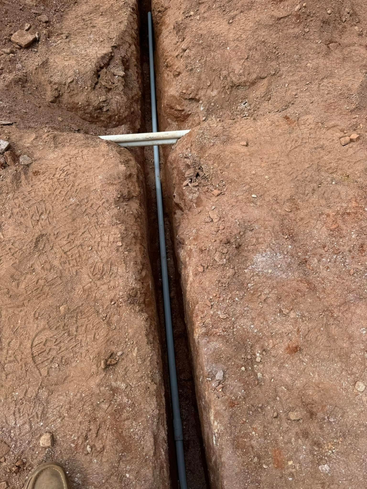 Black cable clipped to a dirt surface with a white cross-shaped marker.