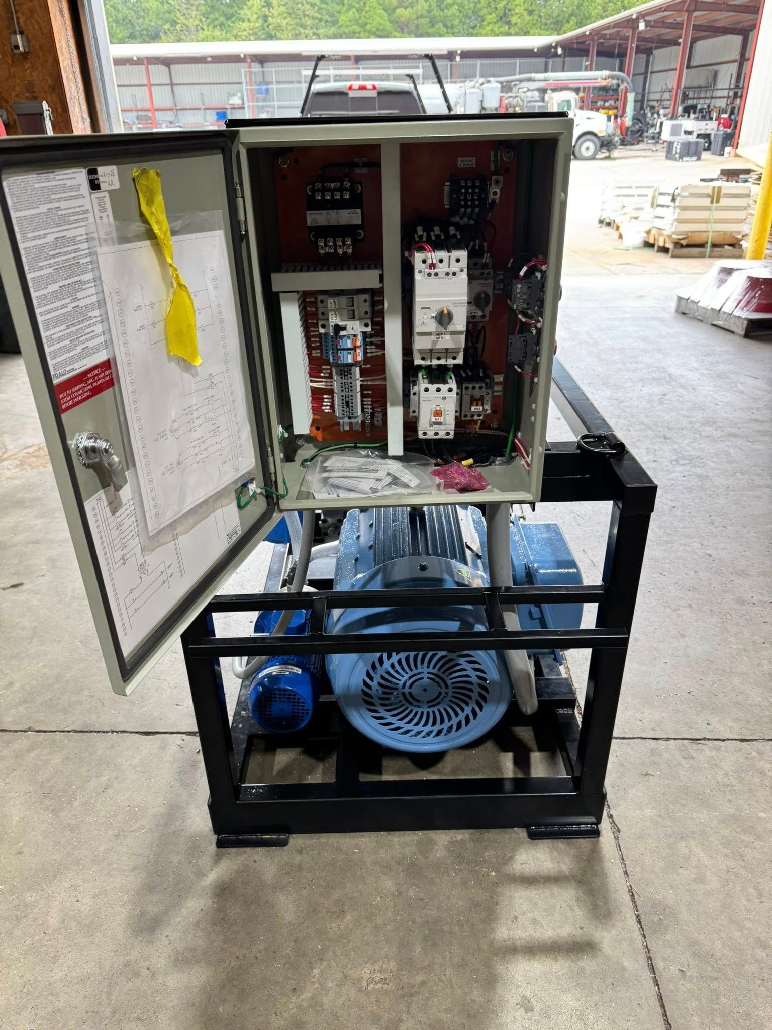 Open electrical control cabinet on a blue-framed machine in a workshop.