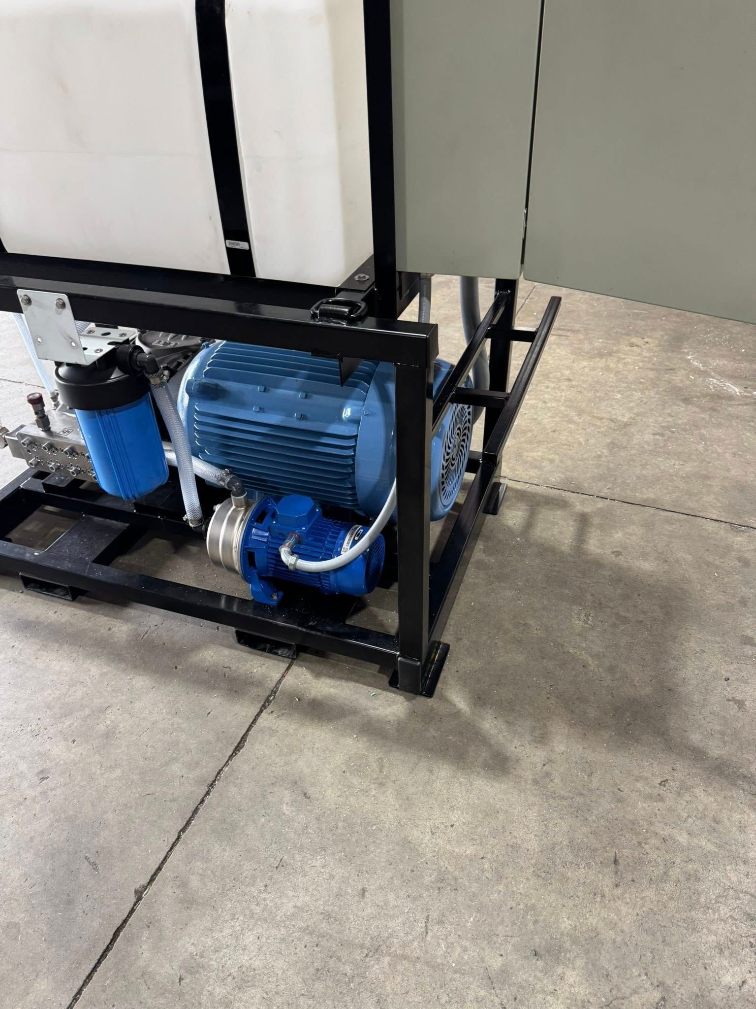 Blue motor and pump mounted on a black metal frame outdoors on concrete.