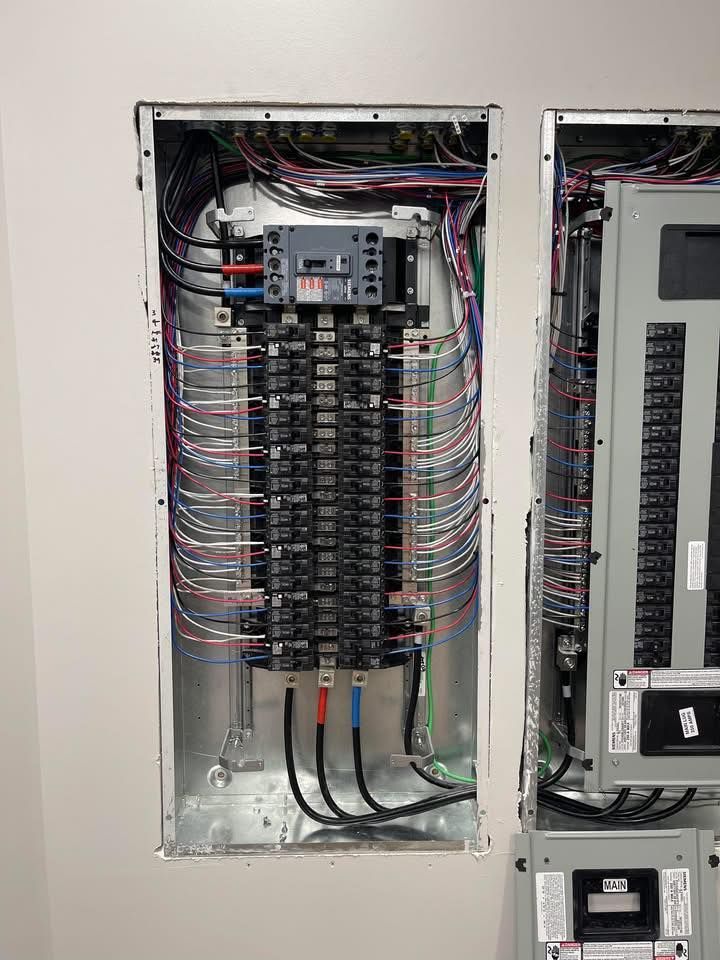 Electrical breaker panel with many labeled wires and circuit breakers inside a metal cabinet.