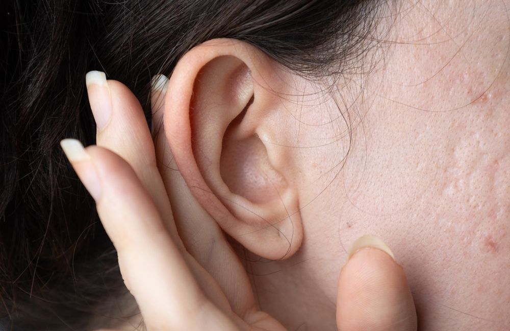 A woman is covering her ear with her hand.