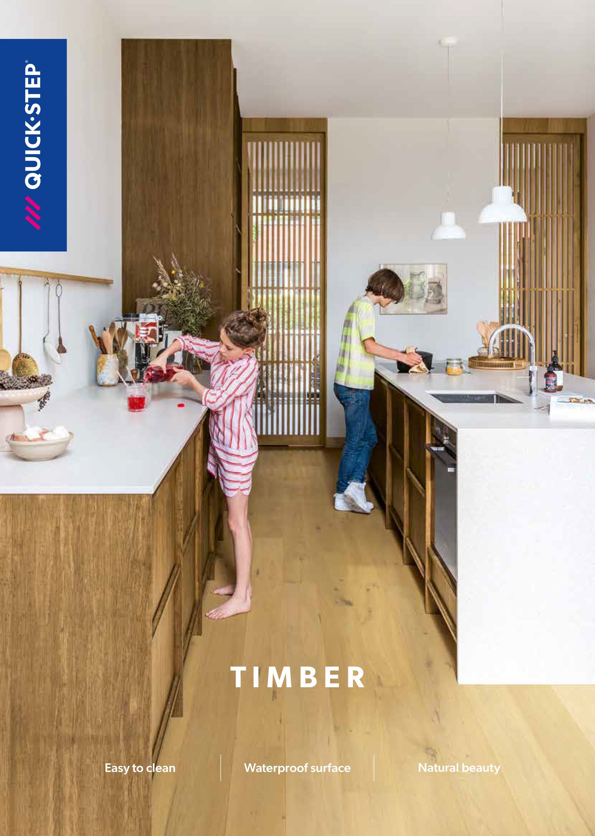 Kitchen with kids; one making drink, one prepping food; cabinets and island, wood and white countertops.