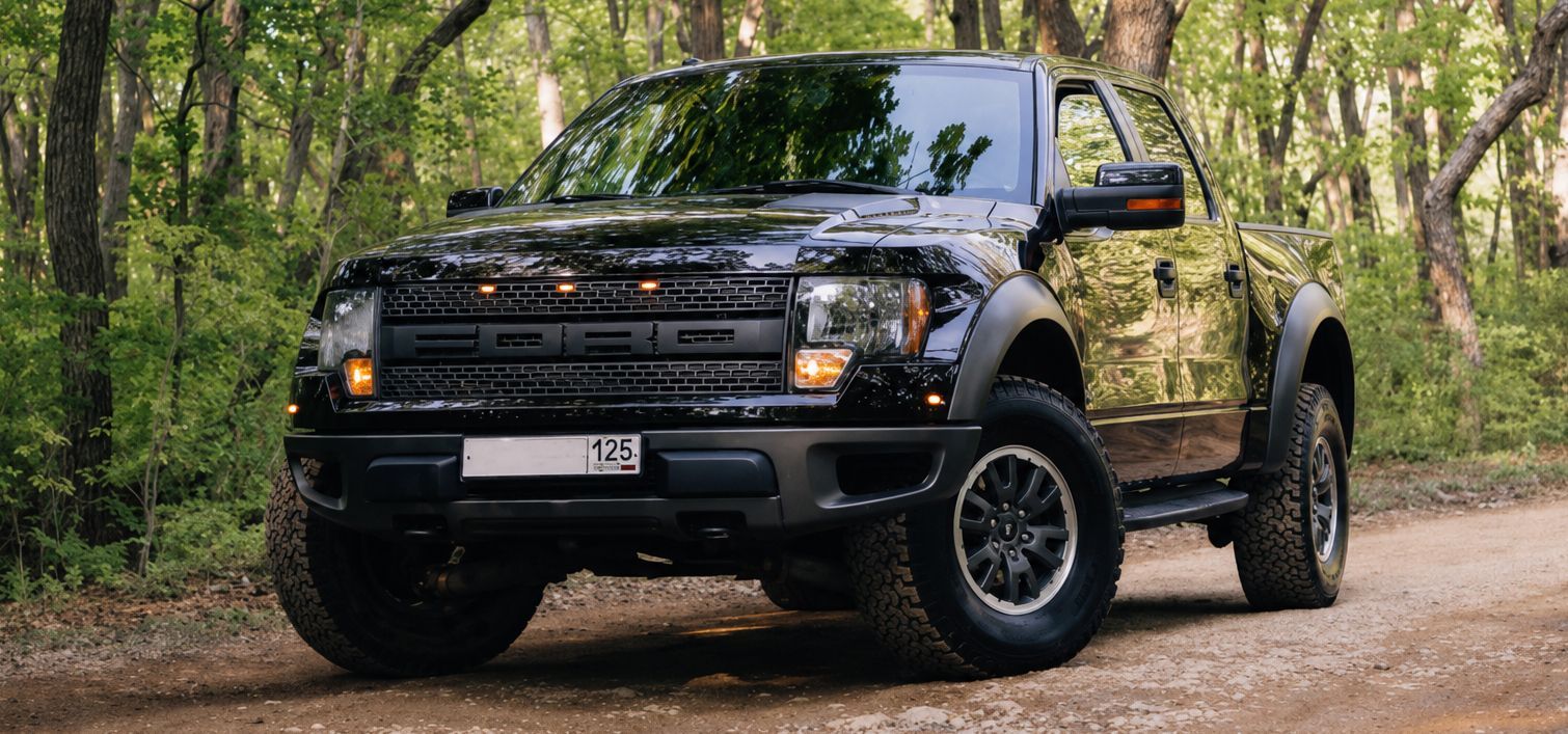 Black pickup truck parked on a dirt path in a wooded area