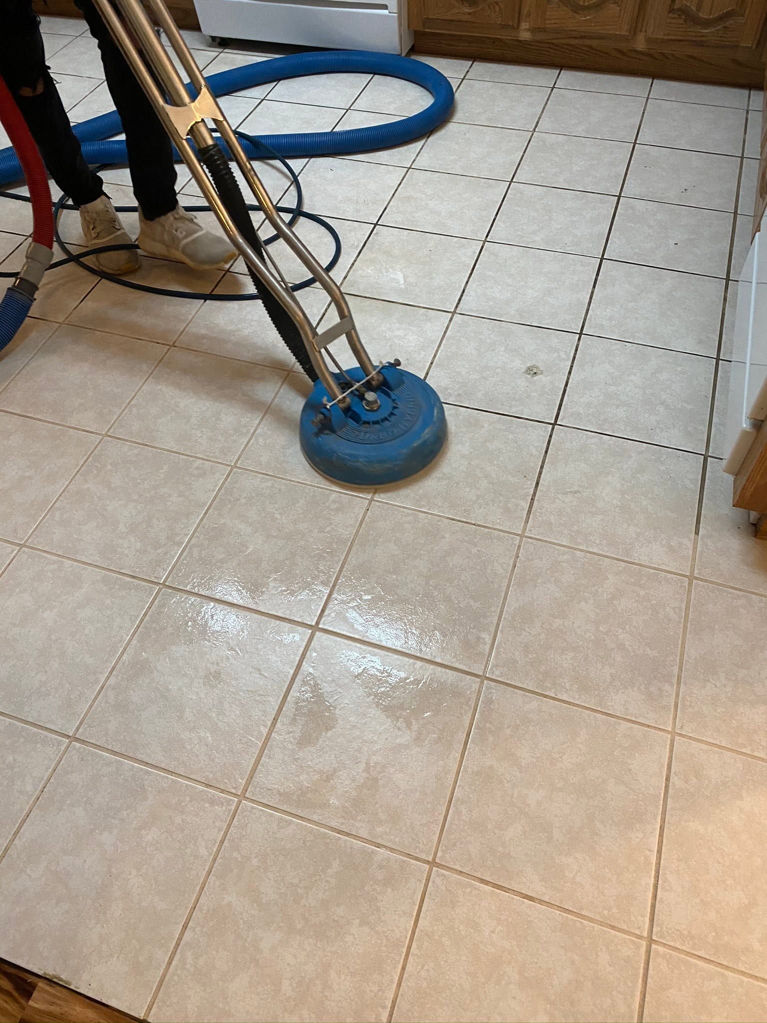 Floor-cleaning machine scrubbing wet tiled floor indoors