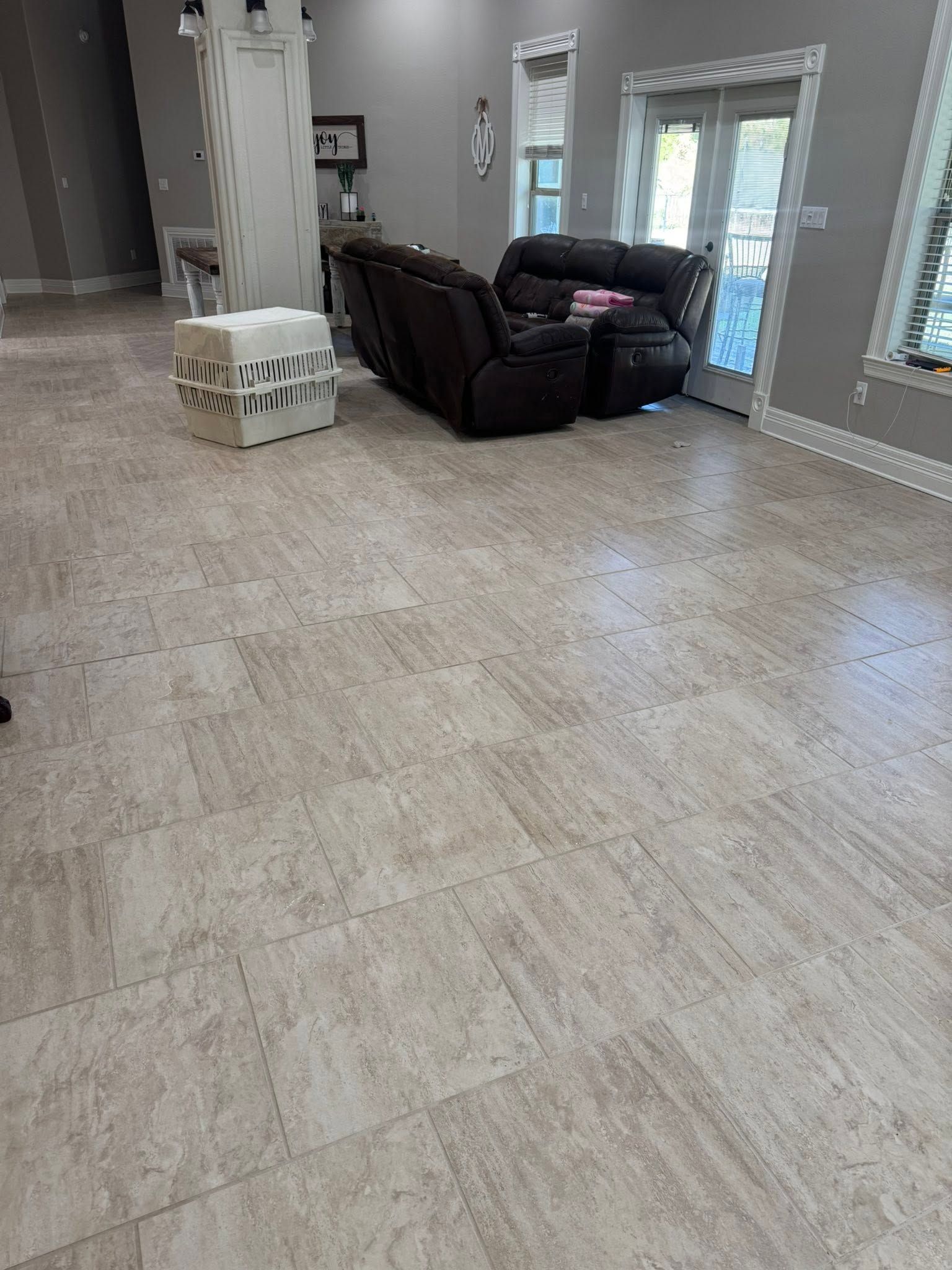 Empty beige living room with recliner, white chair, and bright windows.